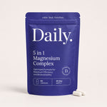A blue stand-up pouch labeled 'Daily. 5 in 1 Magnesium Complex' on a light beige background, with two white capsules placed in front.