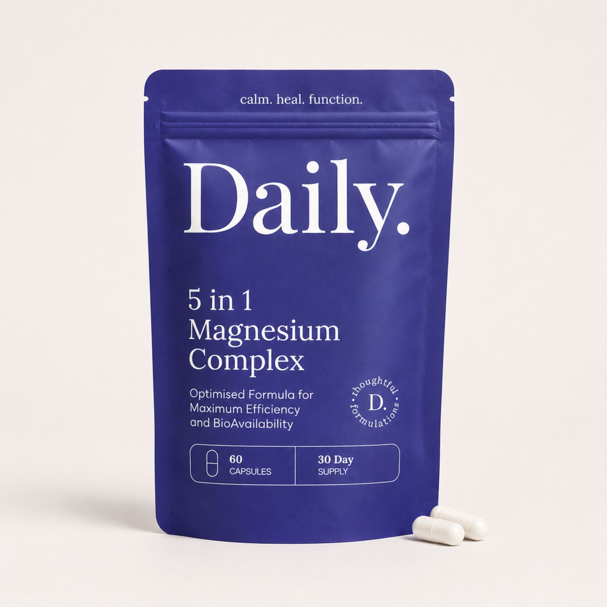 A blue stand-up pouch labeled 'Daily. 5 in 1 Magnesium Complex' on a light beige background, with two white capsules placed in front.